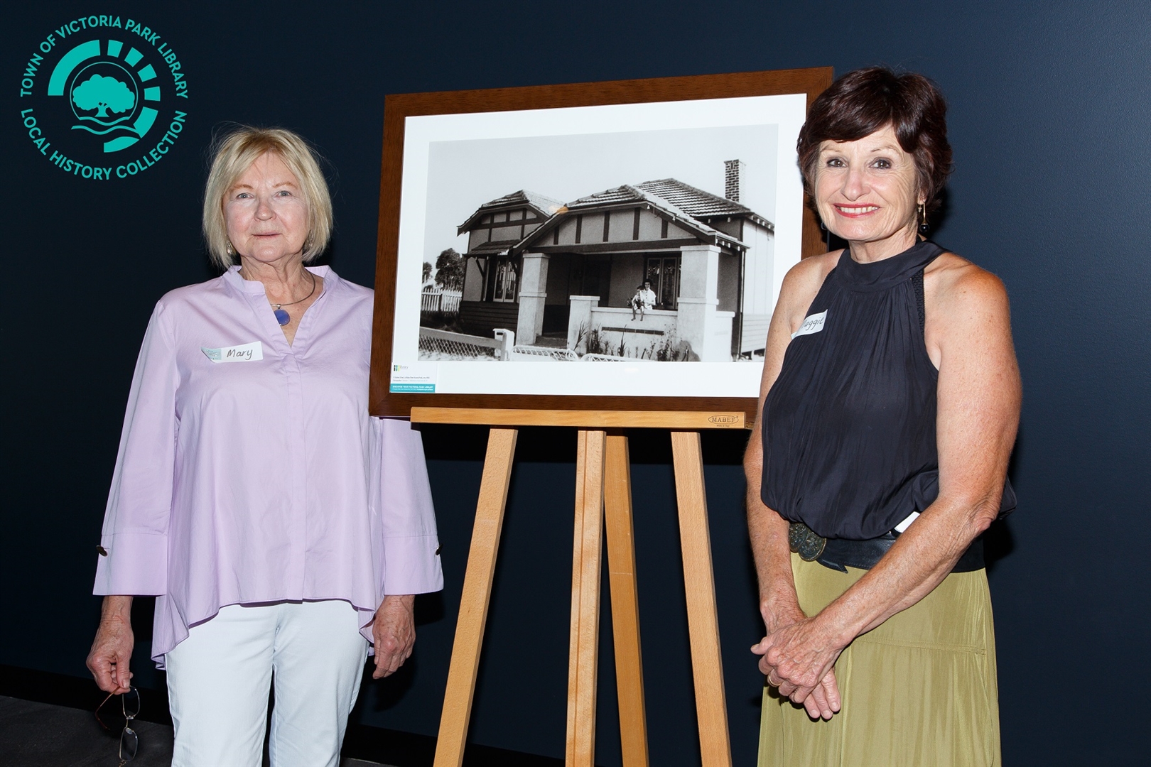 PH00035-46 Mary Jolob and Maggie DeGroot in front of framed photograph RoTP No 19 2020 Town Faithful Image
