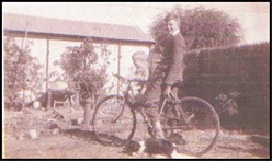 John and Alec Bell sitting on a bicycle with 'Pip' the dog resting on the ground, circa early 1950s. In the backyard of 953 Albany Highway, East Victoria Park.